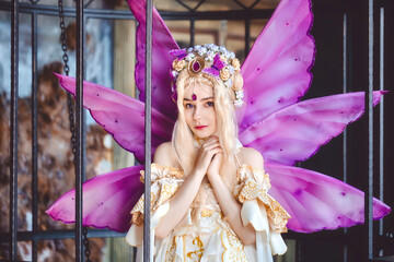 Young attractive girl dressed as fairy in the cage