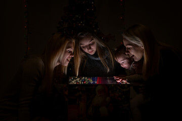 Little girl with her mother and two aunts looks for a miracle in the magic box © LuMo photography