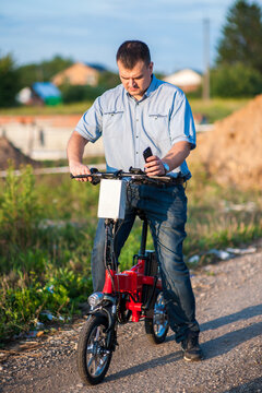 Male businessman with mobile phone on an electric bike.