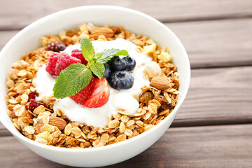 Tasty granola with fresh berries on brown wooden background