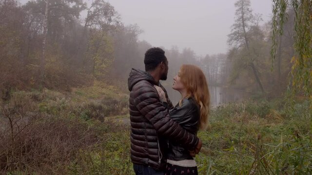 Interracial love concept. Beautiful young interracial couple posing in the foggy autumn park