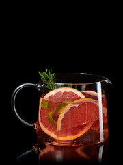Fresh homemade lemonade with grapefruit and rosemary in the glass carafe isolated on black background