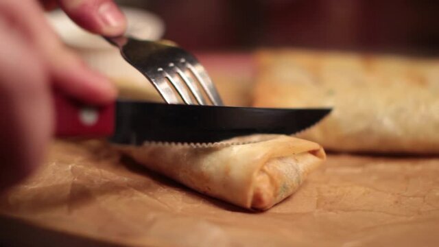 person slicing a spring roll
