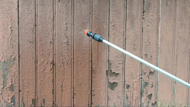 Treatment of an old house with insecticides from termite ants. The spray gun processes old boards with peeling paint