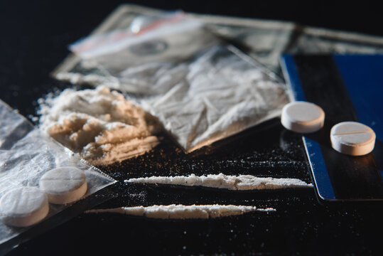 Cocaine drug powder bag and pile and pills on black background