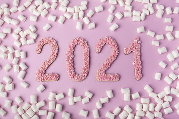 Confectionery concept congratulations with 2021. Confectionery sprinkles in the shape of the number 2021 and marshmallows on a pink background. High quality photo