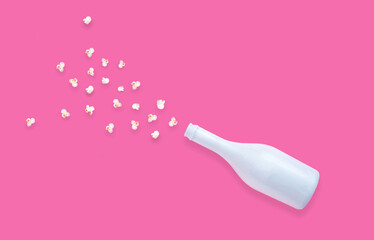 Creative concept with champaign bottle and popcorn on pastel pink background. Flat lay design