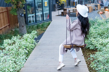 Woman riding swing near a cafe