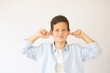 Don't want to hear! Angry young boy in stylish shirt with hood closing ears with fingers,...