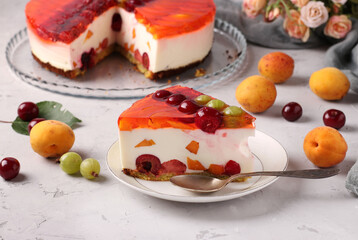 Homemade jelly cake with berries on gray background and slice cake on a plate on foreground. Horizontal format