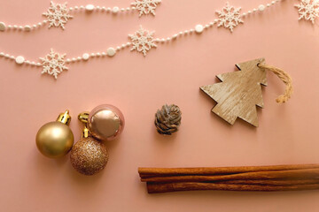 Various Christmas decorations and cinnamon sticks on pink background. Flat lay.