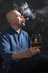 Solid bald man in shirt with glass of whisky and fume