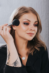 Fototapeta premium Beautiful young woman putting make up on herself.