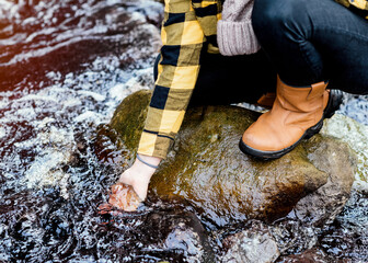 woman in yellow shirt and hat sitting on the river bank in the autumn forest