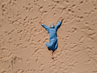 Funny set: Tired female doctor in medical gear lying on sandy beach
