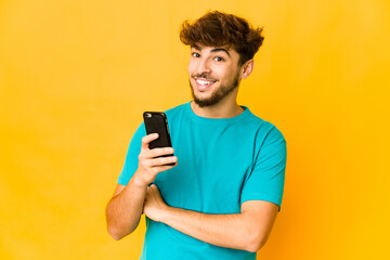 Young indian man holding a phone laughing and having fun.