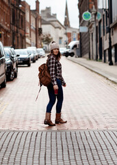 woman in a shirt with backpack waiting for a bus on bus stop
