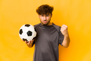 Young soccer player indian man showing fist to camera, aggressive facial expression.