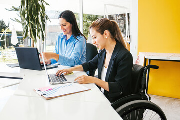 Disabled young latin businesswoman using computer in creative office