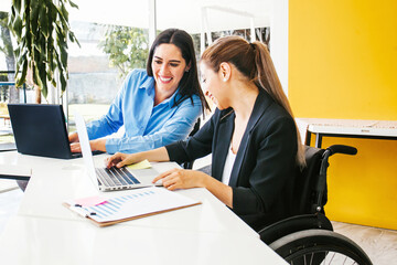 Hispanic woman in wheelchair with her colleagues at workplace in Latin America