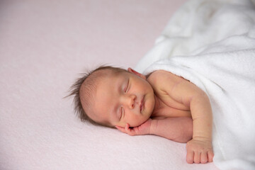 A cute little newborn baby is sleeping on a blanket.