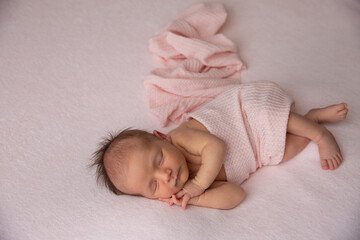 A cute little newborn baby is sleeping on a blanket.