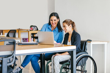 Disabled Mexican female sitting at office desk, working on laptop in Mexico city

