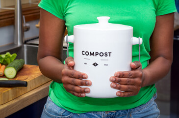 Close up of hands of black African Australian woman holding a kitchen compost container in kitchen, recycle kitchen food waste for zero waste sustainable living