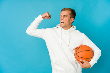 Young caucasian man playing basketball isolated on blue background