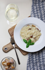 Vegetarian gourmet mushroom risotto on a white plate, yellow background, served with a glass of white wine. A northern Italian rice dish cooked with broth until it reaches a creamy consistency. - 396659673