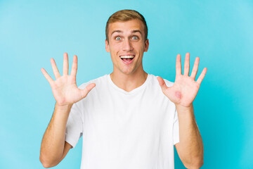 Young caucasian handsome man receiving a pleasant surprise, excited and raising hands.