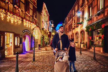 Obraz premium family walking among decorated streets of Kaysersberg village on Christmas holidays. Alsace, France
