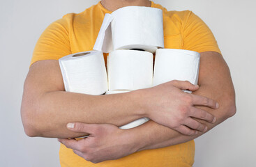 People are stocking up toilet paper for home quarantine from coronavirus. Man holds many rolls of...