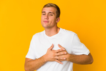 Young caucasian handsome man has friendly expression, pressing palm to chest. Love concept.