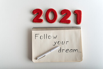 Top view numbers 2021 and notebook with words: FOLLOW YOUR DREAM. Wishlist for 2021