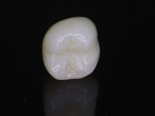 Macro shot of zirconia crown on dark background with reflection