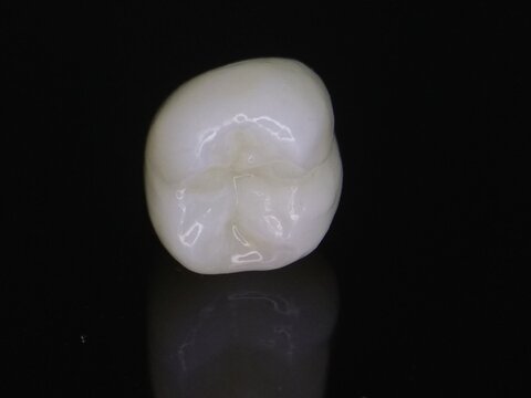 Macro shot of zirconia crown on dark background with reflection