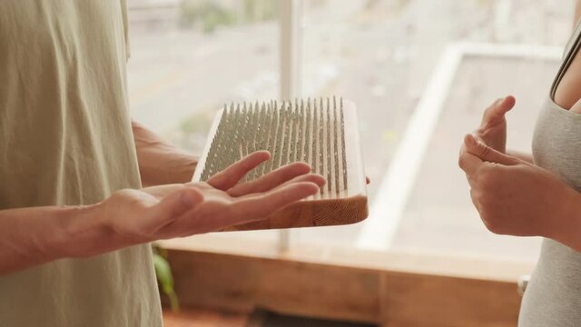 Midsection footage of young yogis holding wooden board with metal sharp nails for practicing yoga in studio with panoramic windows