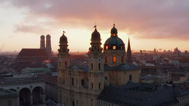 Aerial Slide by Stunning Yellow Theatine Church Cathedral Building in Golden Hour Sunset light, Munich Cityscape in distance