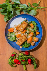 Healthy plate with fried vegetarian tofu and greek halloumi with grilled vegetables and yogurt sauce. Mediterranean food dishes with oriental couscous. Lemons and hot peppers around in decorative way
