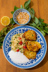 Healthy plate with fried vegetables meatballs and yogurt sauce. Mediterranean food dishes with oriental couscous with peppers and garlic. Lemons and peanuts around in decorative way. Food Background