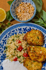 Healthy plate with fried vegetables meatballs and yogurt sauce. Mediterranean food dishes with oriental couscous with peppers and garlic. Lemons and peanuts around in decorative way. Food Background