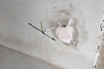 The wires are sticking out of the wall. Repair in the apartment. electrical wires with connectors protrude from the plasterboard wall prepared for the installation of lighting equipment