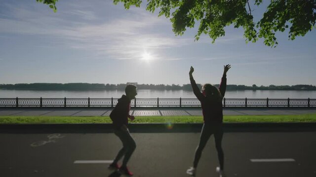 Silhouettes of guy and girl completing running distance in outdoors. Young couple doing sports or fitness together. Guys happy at finish line. Man and woman preparing for marathon. Lifestyle concept.