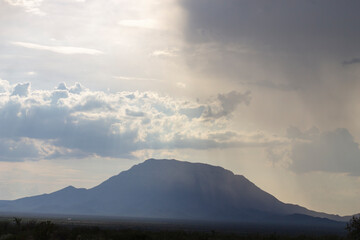 montañas obscuras, cielo nublado, nubes obscuras, lluvia a lo lejos.
