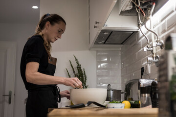 Young charming Swedish woman cooking at home in her kitchen, preparing healthy mediterranean food...