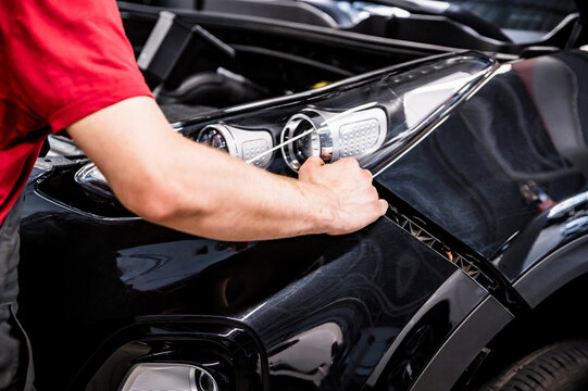 Close-up of mechanic hands dismantling the bumper of the car
