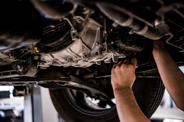 Fototapeta na wymiar Close up of a mechanic hands repaires lifted car