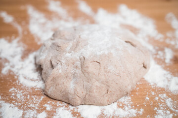 Homemade pizza dough close up on a wooden board with flour. Delicious typical italian recipe.