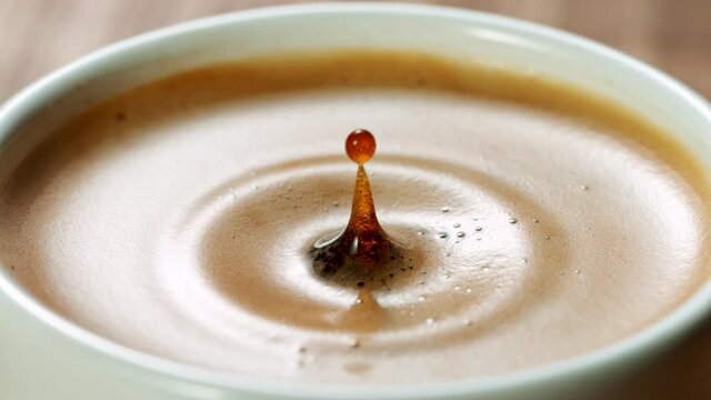 Super Slow Motion Detail Shot of Coffe Drop Falling into Fresh Espresso at 1000 fps.